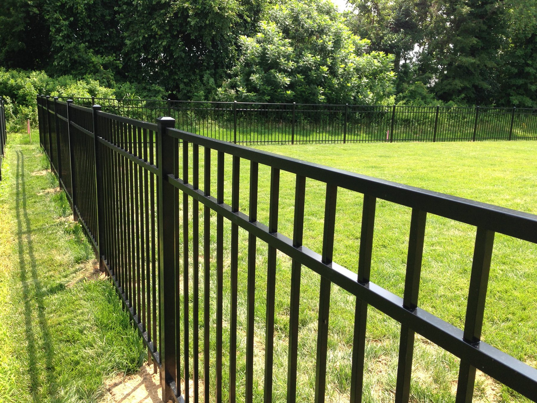 Close-up of black powder-coated aluminum fence pickets and rail